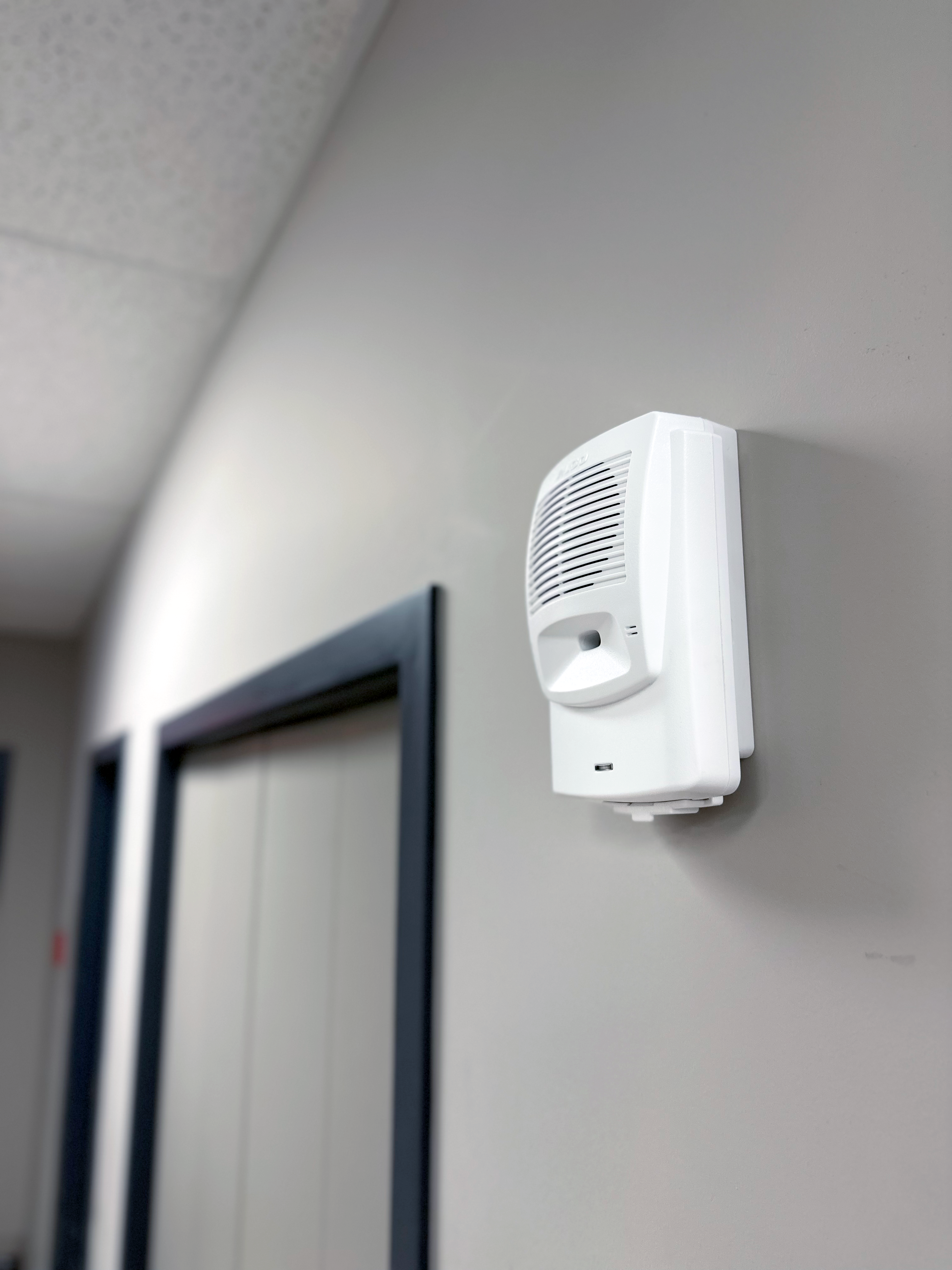 Photo d'un avertisseur sonore Algo 8180 fixé au mur d'un couloir pour diffuser des alertes sonores puissantes.