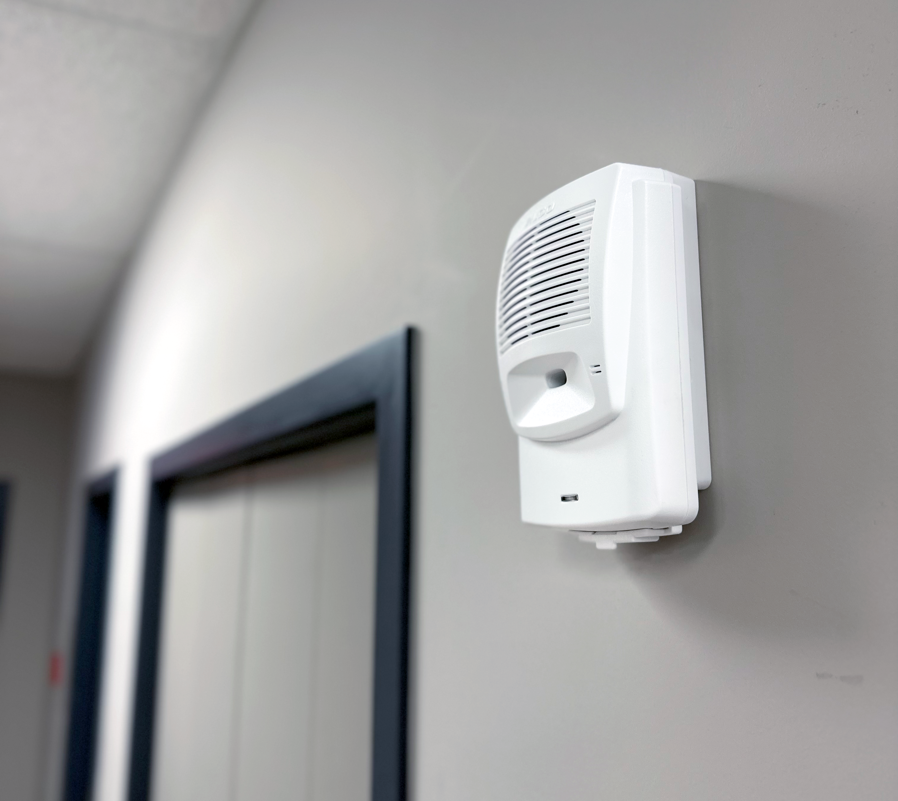 Photo d'un avertisseur sonore Algo 8180 fixé au mur dans un couloir pour diffuser des alertes sonores puissantes.