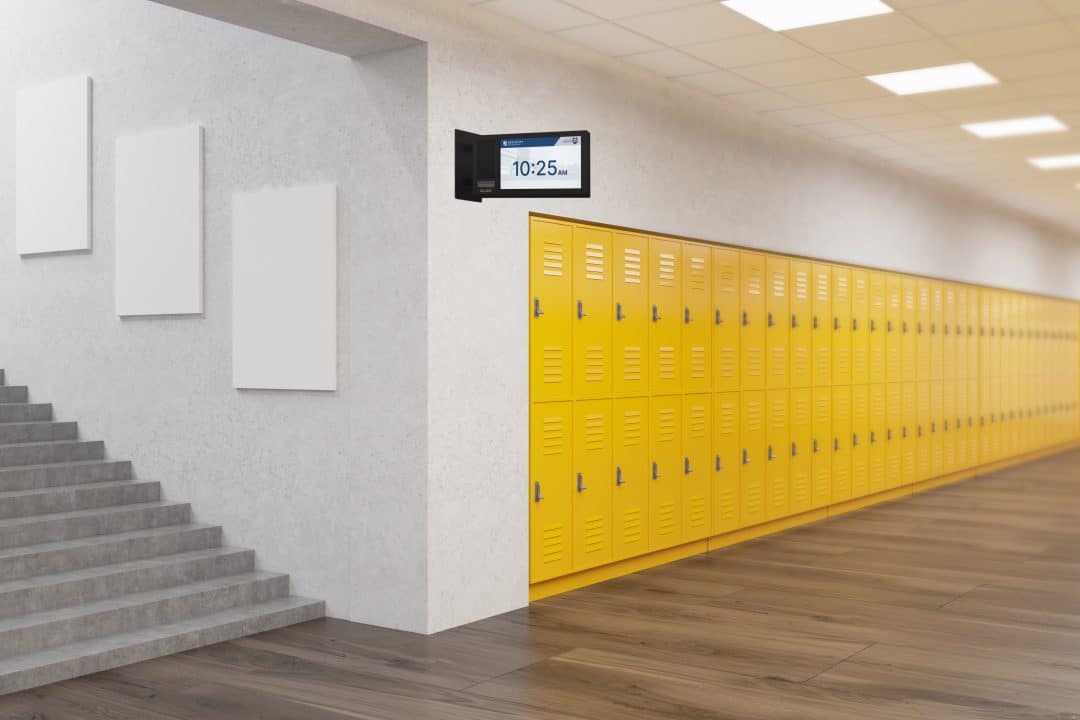 Image of an Algo 8420 display speaker which is double-sided and mounted to a wall in the hallway of a school displaying the time.