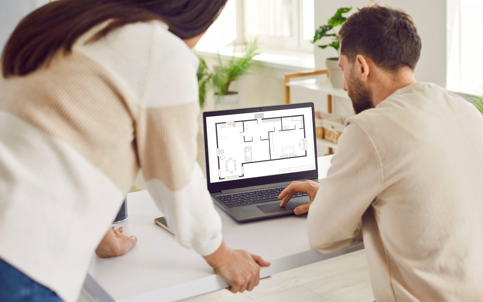 Two people working with design services project of commercial space looking at blueprint of company floor plan.